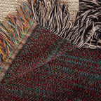 The Mountain Lake woven cotton blanket folded back at the corner to show the reverse weave and the colourful fringe along the hem.