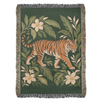 Tiger Botanical woven cotton blanket shown full front: a striding orange tiger among cream blossoms and green leaves on deep green, with fringe.