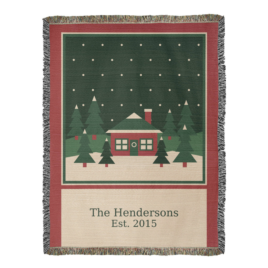Personalized family name Christmas woven cotton blanket, full front with red cabin, evergreens, family name and year