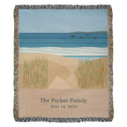 Coastal personalized woven cotton blanket shown full front: sea, white surf and dune grass with "The Parker Family" and June 14, 2020 woven on the sand-coloured panel.