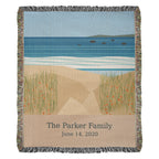 Coastal personalized woven cotton blanket, 50 by 60 inches, shown full front: sea, white surf and dune grass with "The Parker Family" and June 14, 2020 woven on the sand-coloured panel.