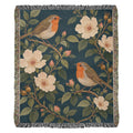 Bird Garden woven cotton blanket shown full front on a white background: robins perched on flowering branches with cream wild roses on deep teal, with fringed edges.