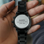Engraved black watch caseback held in hand with DANIEL, SO PROUD OF YOU, LOVE, DAD