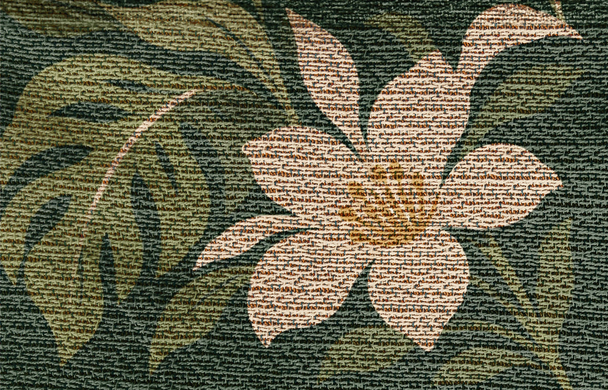 Close-up of the Tiger Botanical woven cotton blanket: a cream blossom among deep green leaves, showing the texture of the cotton weave.