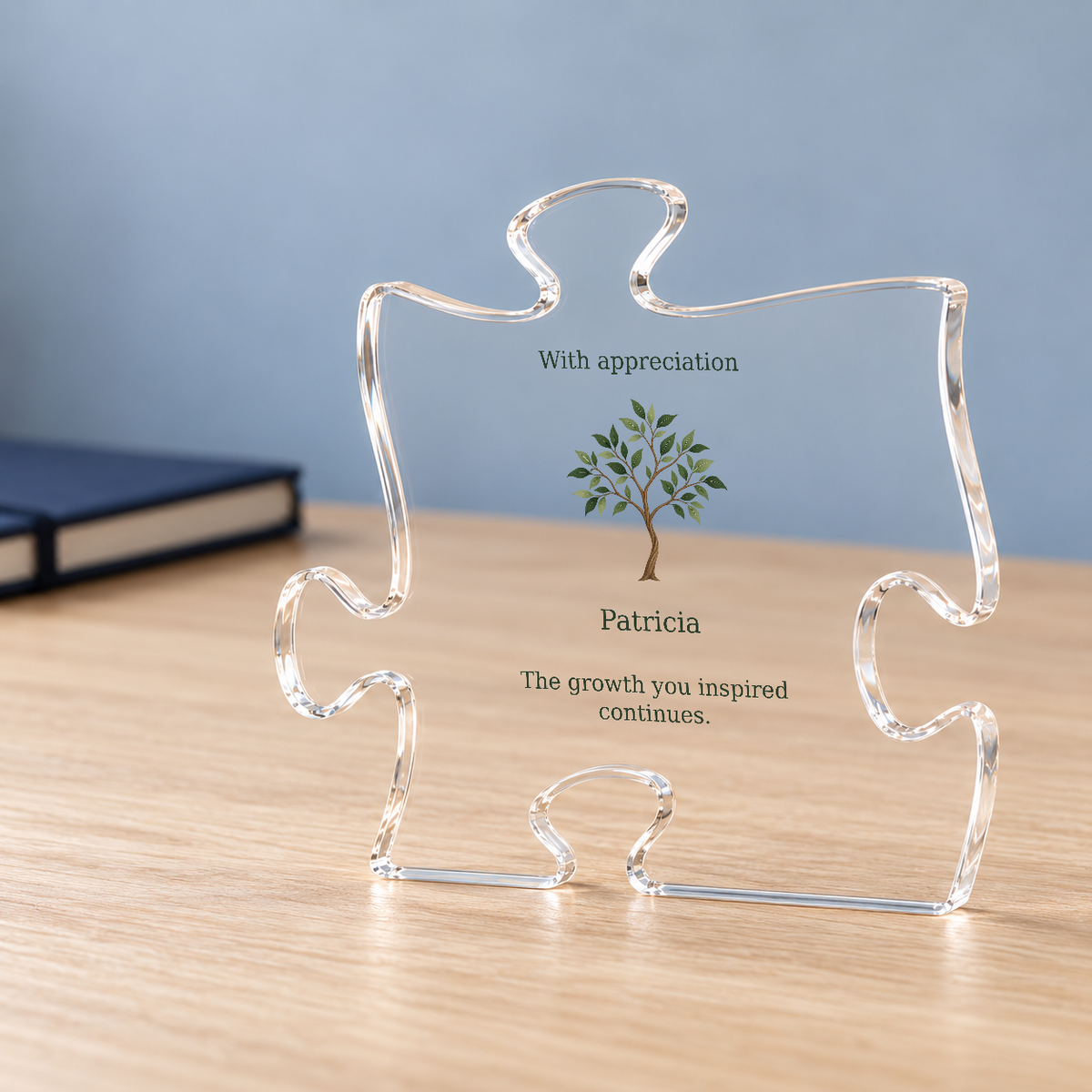 Angled puzzle plaque on a wooden desk showing sapling art, Patricia and The growth you inspired continues.