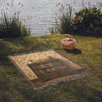 Library cat woven throw: orange tabby folk art laid on a lakeside picnic lawn, seen at an angle