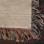 Corner close-up of the Cabin woven cotton blanket showing the cream cotton weave, the multicolour fringe along the bottom edge and the black-and-white side fringe.