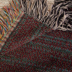 The Cabin woven cotton blanket folded back at the corner to show the reverse weave and the colourful fringe along the hem.