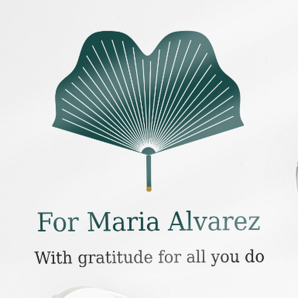 Close-up of the printed text on the clear acrylic puzzle-piece caregiver plaque reading "For Maria Alvarez" and "With gratitude for all you do"