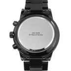 Back of a black chronograph watch with brushed steel caseback on a white background, caseback engraved "John Smith 35 Years of Service"