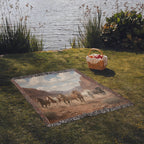 Western horse woven cotton throw laid on the grass by a lake, fringed edges, canyon herd design facing up