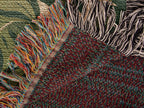 Folded corner of the Tiger Botanical woven cotton blanket showing the diagonal fold, stitched hem, both fringes and the woven reverse side.