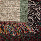 Close-up of the woven cotton blanket corner: textured cream weave, sage border and multicolor knotted fringe