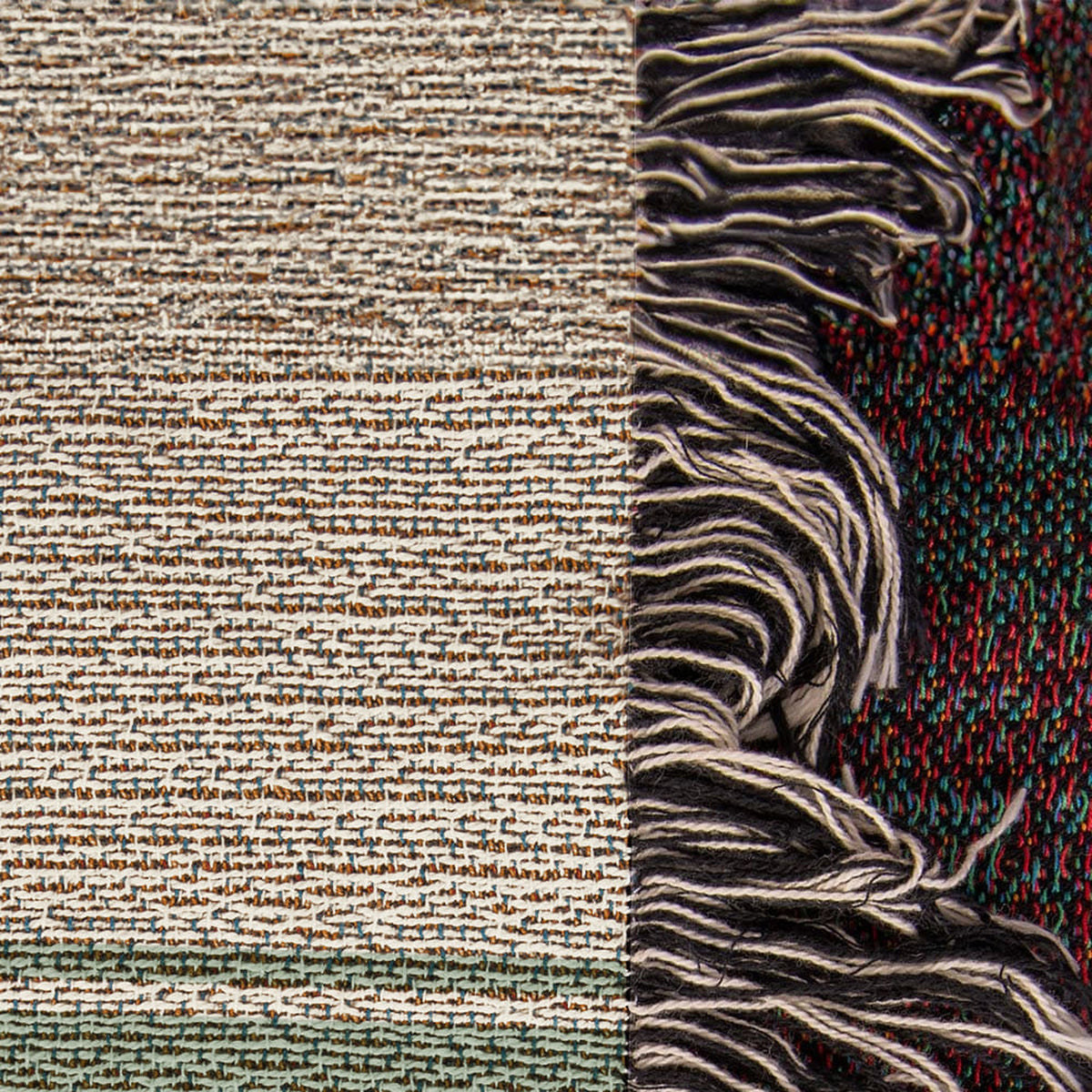 Close-up of the woven cotton blanket edge: textured cream weave and multicolor knotted fringe