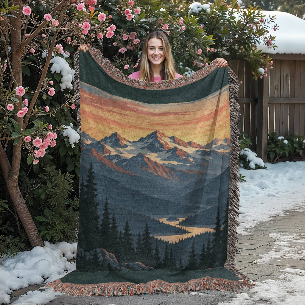 Mountain Sunrise woven blanket held up in a flowering garden, showing the whole sunrise mountain design and the fringed edges.