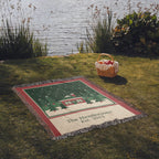 Personalized Christmas woven blanket laid on a lakeside lawn with a picnic basket, family name and year in the cream band