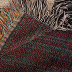 The Family Caravan woven cotton blanket folded back at the corner to show the reverse weave and the colourful fringe along the hem.