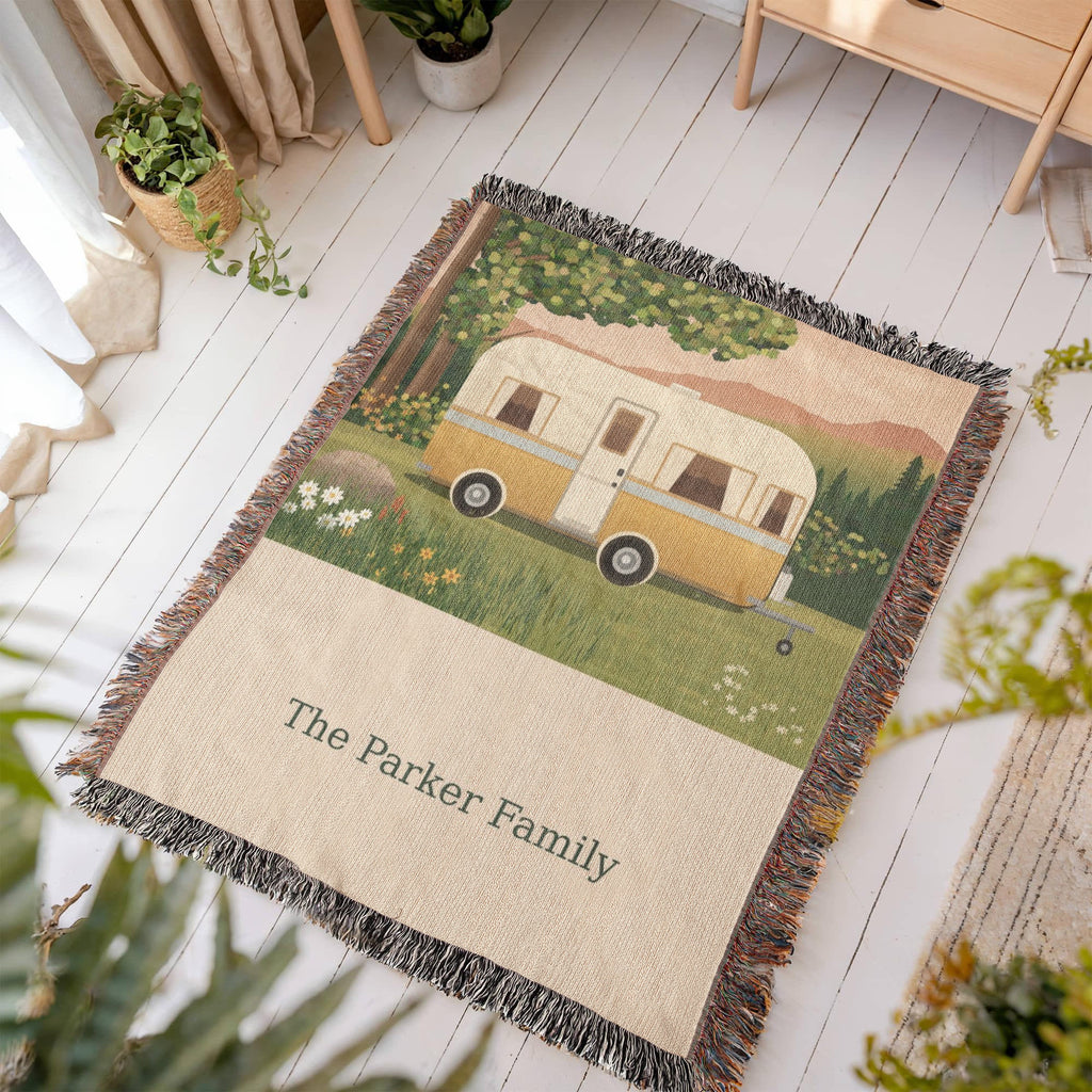Family Caravan personalized woven cotton blanket laid flat on a white wooden floor in a sunny room, showing the whole design and fringe.