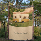 Family Caravan personalized woven cotton blanket pegged on a clothesline among trees, showing the whole design and the woven names.