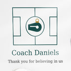 Close-up of the printed text on the clear acrylic puzzle-piece coach plaque reading "Coach Daniels" and "Thank you for believing in us"