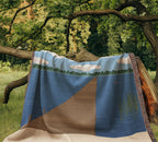 Lake House personalized woven cotton blanket draped over a low tree branch in a green garden, the woven lake, dock and sky scene facing forward.