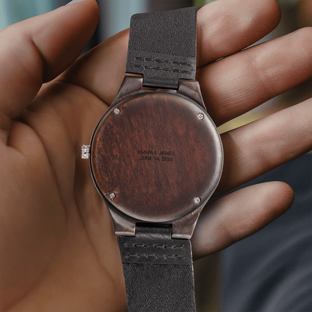Wooden engraved watch held in hand, back engraved in capitals EMMA & JAMES / JUNE 14, 2026