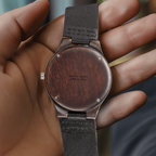 Wooden engraved watch held in hand, back engraved in capitals EMMA & JAMES / JUNE 14, 2026