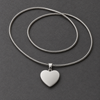 Smooth polished steel back of the heart pendant with the full snake chain on a dark gray surface