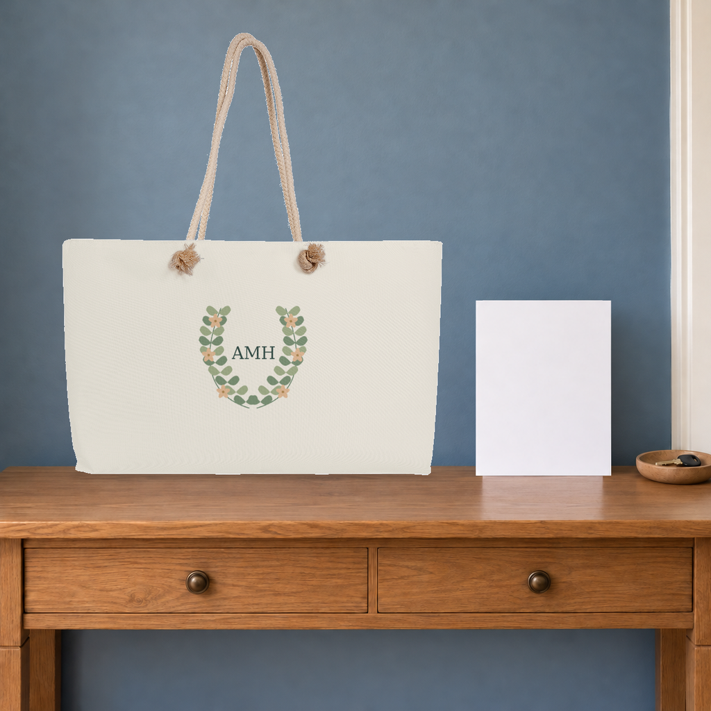 AMH botanical cream-rope weekender on a wooden console in a composed travel setting.