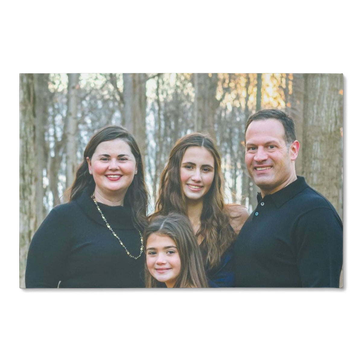 Custom family portrait canvas from one photo, front view of a gallery-wrapped canvas showing a smiling mother, father and two daughters in an autumn wood.