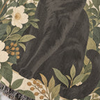 Angled woven cotton blanket detail showing the black cat's paws and curled tail