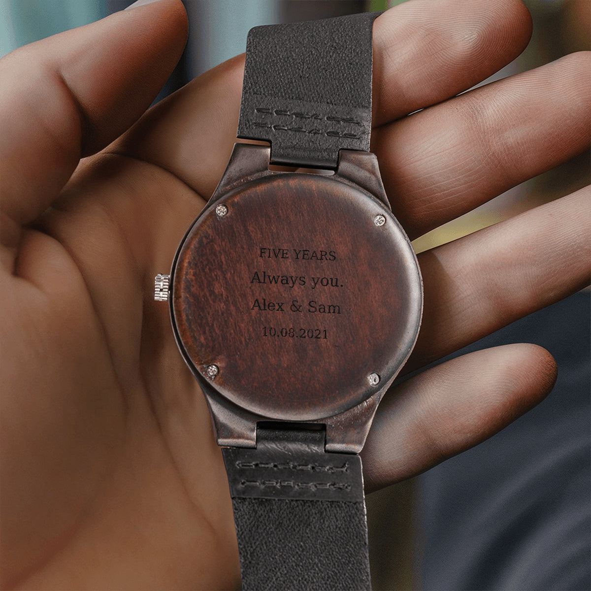 Personalized wooden watch caseback held in a hand