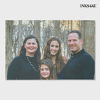 Custom family portrait canvas of a family of four, printed edge to edge and gallery-wrapped, shown from the front and leaning on a wood floor.