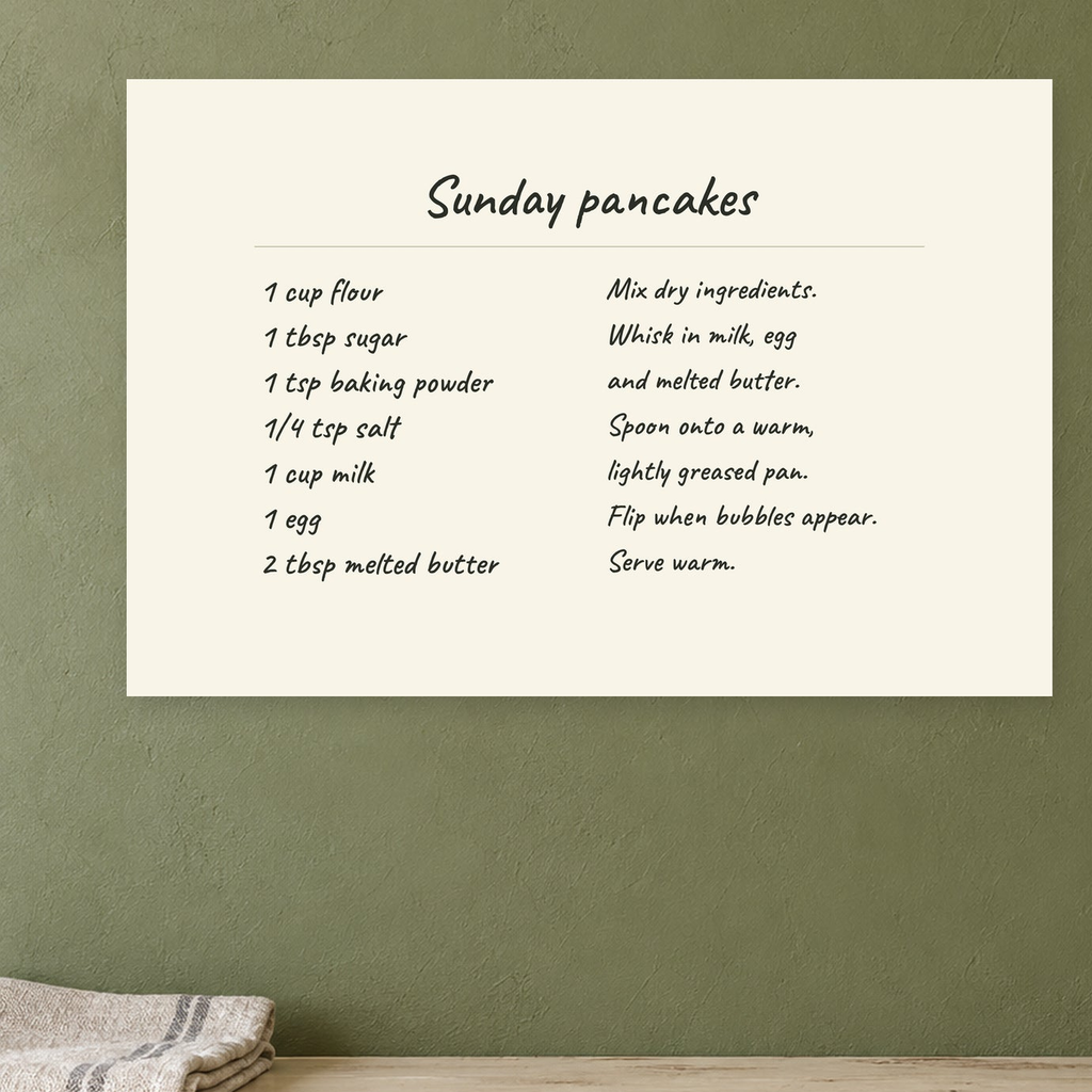 Sunday pancakes recipe canvas hanging on an olive kitchen wall above a cream counter.